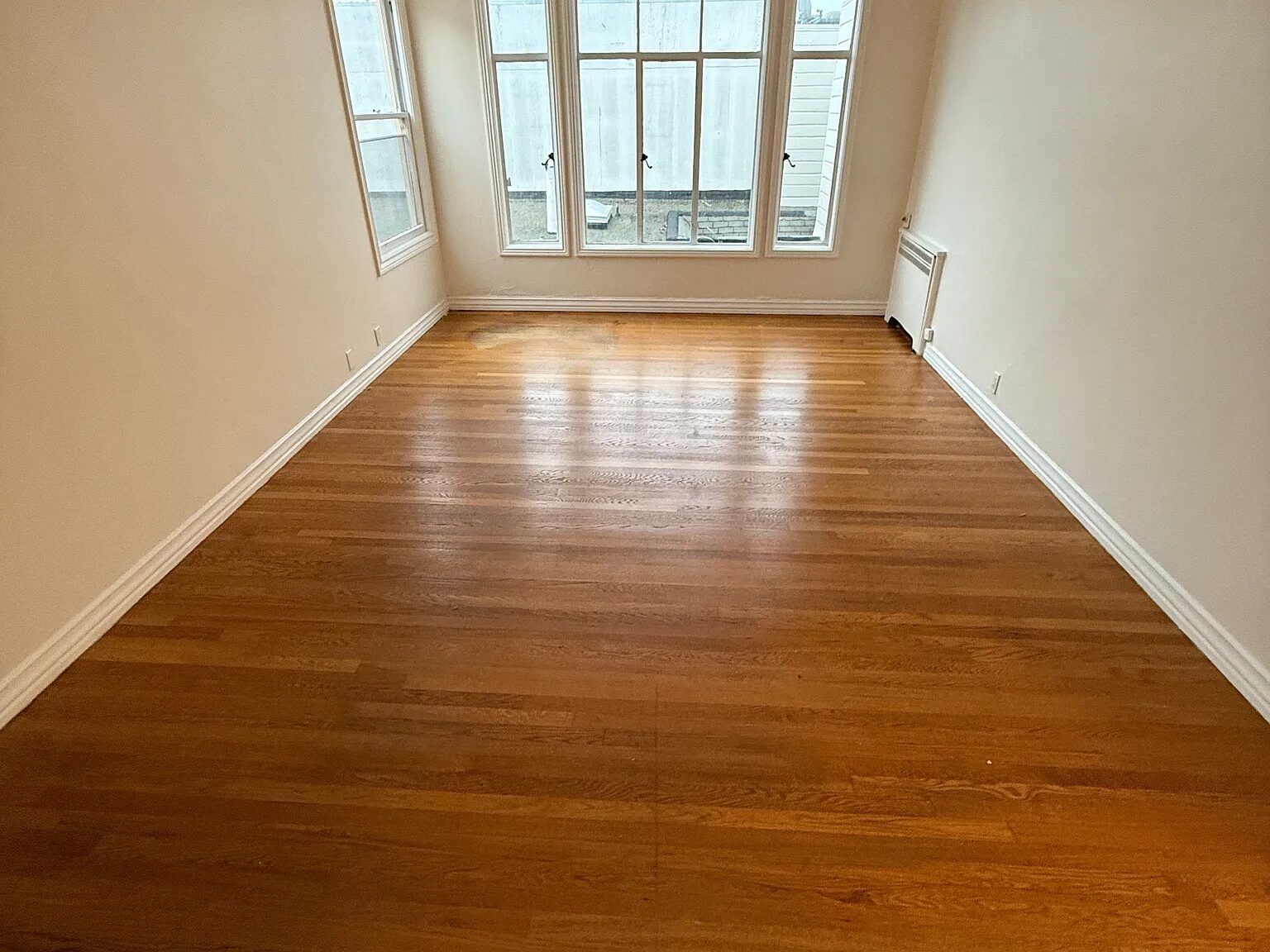 Living room with a bank of tall windows and refinished oak floors