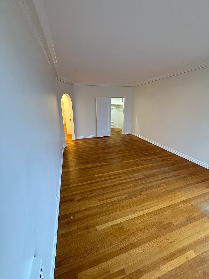 Room looking toward the arched doorway with the closet standing open