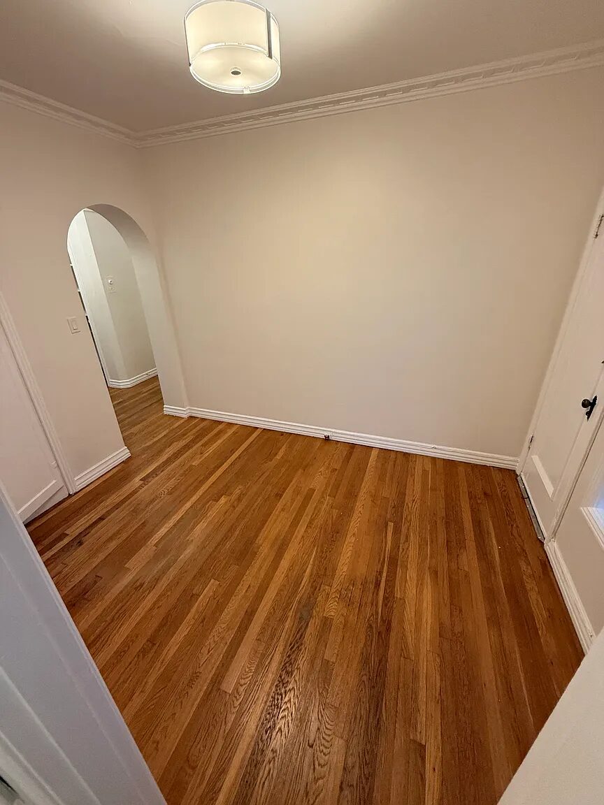 Second room with crown moulding, ceiling light and an arched opening