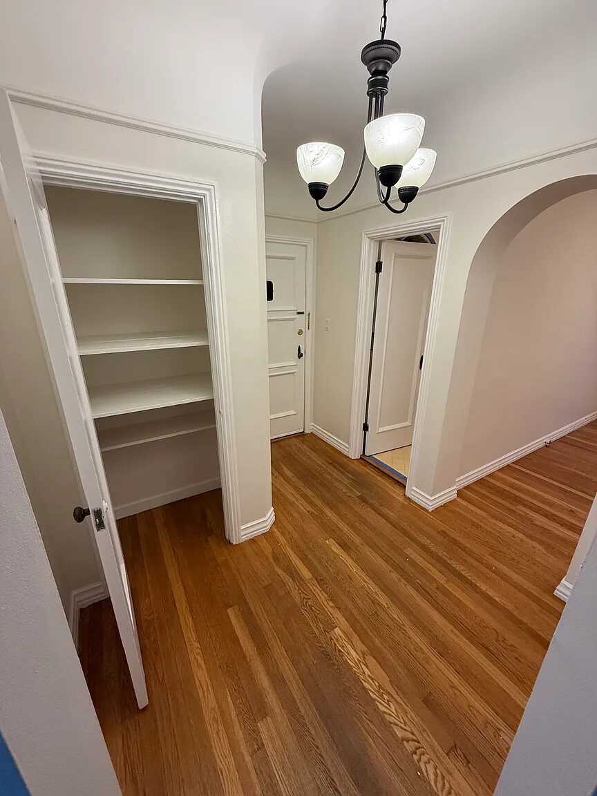 Entry hall with chandelier, shelved linen closet and front door