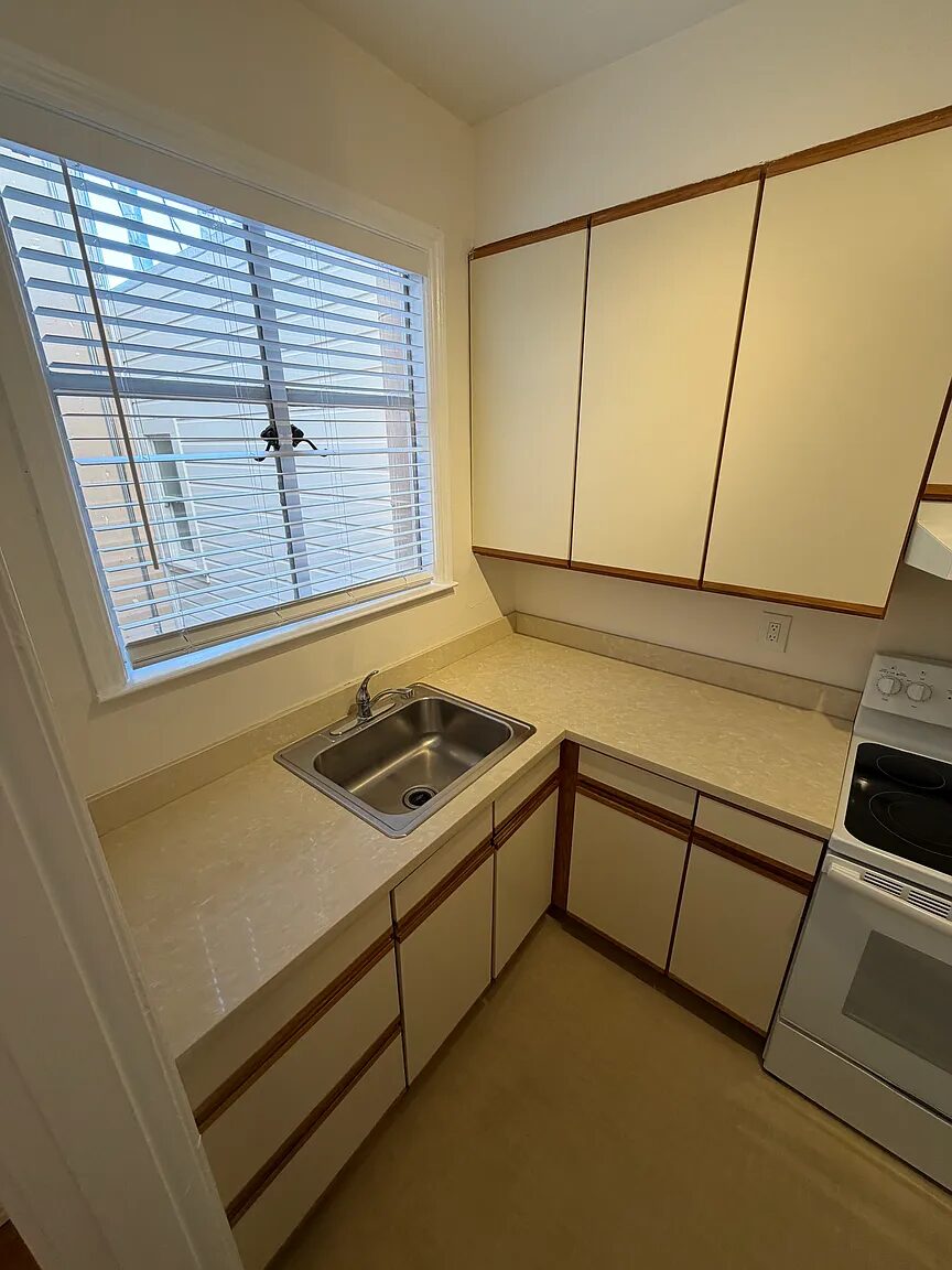 Kitchen with stainless sink below a window and full upper cabinets