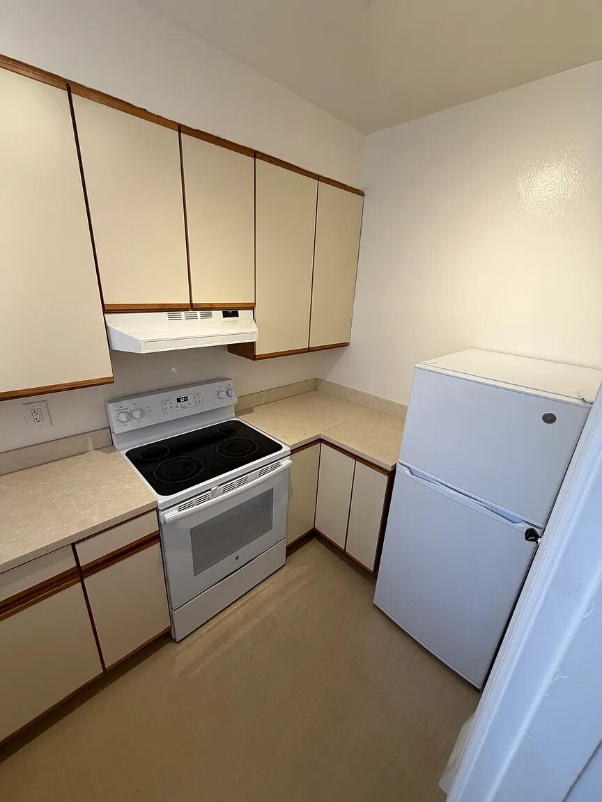 Kitchen with electric range, vent hood and refrigerator