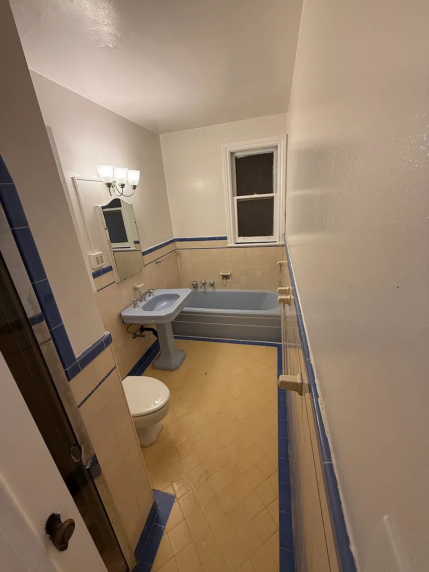 Tiled bathroom with a soaking tub, pedestal sink and window