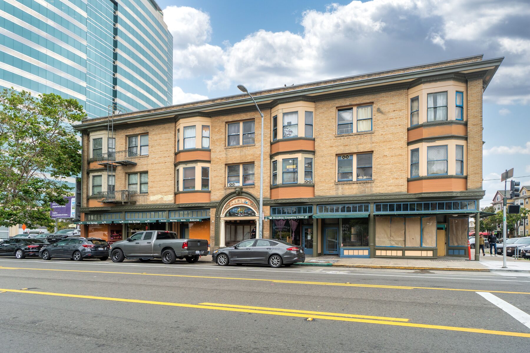 Three-story tan brick building with green awnings and ground-floor storefronts